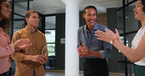 Diverse coworkers celebrating employee achievement in office