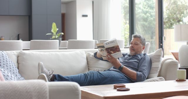 Senior man relaxing on sofa reading magazine in modern living room - Download Free Stock Images Pikwizard.com