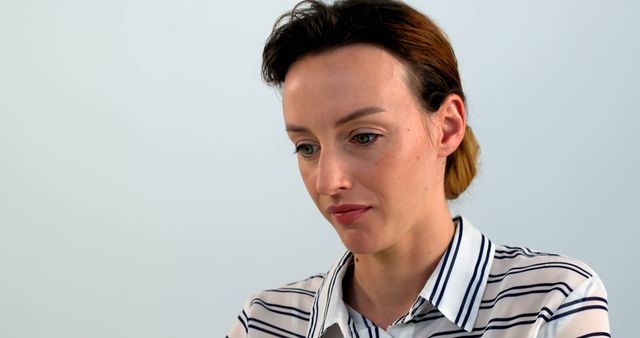 Pensive woman in striped shirt looking down - Download Free Stock Images Pikwizard.com