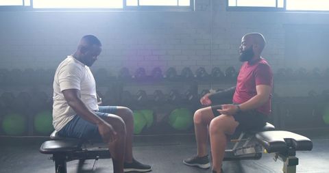 African american trainer coaching client on bench workout and recovery conversation in gym