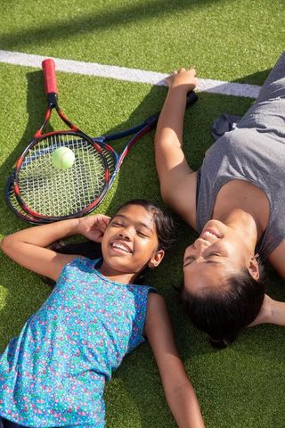 Mother and daughter relaxing on tennis court after match