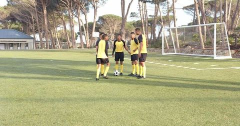 Soccer Team Strategizing on Field Before Practice Session