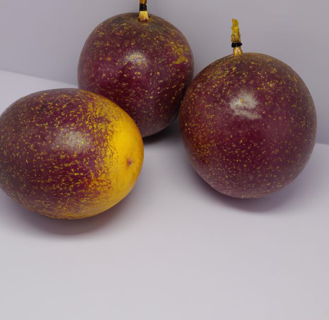 Three ripe passion fruits with purple and yellow speckled skin sit on a white surface. Ideal for marketing materials related to healthy eating, tropical fruits, recipes, or organic produce. Perfect for use in advertisements, food packaging, blogs, or editorial content focused on exotic fruits.