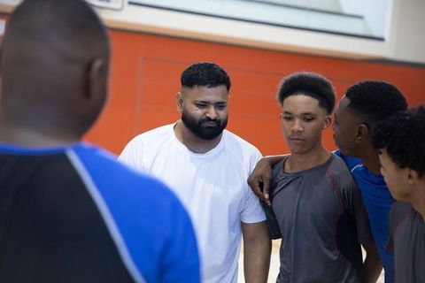 Youth basketball team huddling with coach in gym building teamwork and focus
