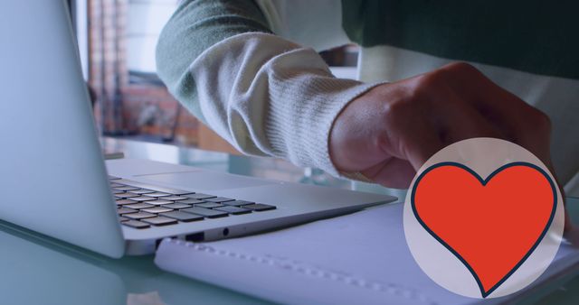 Person typing on a laptop with a red heart symbol overlayed, suggesting the integration of compassion and emotional well-being in the professional setting. Ideal for illustrating themes of work-life balance, mental health, and positivity in the workplace.