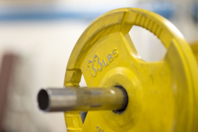 Close-up of a yellow 35 lbs weight plate mounted on gym equipment. Perfect for articles and advertisements on fitness, strength training, and gym facilities. Ideal for use in promotions for gym memberships or fitness-related products.