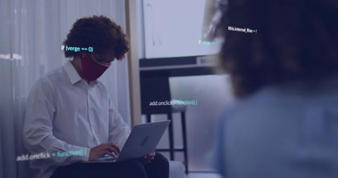 Young professional wearing red face mask typing on laptop with floating code overlay