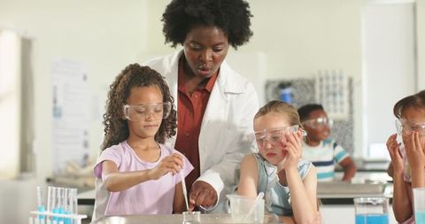 African american teacher guiding kids using pipette in hands-on elementary science lesson