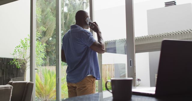 Man talking on phone standing near large sliding glass doors - Download Free Stock Images Pikwizard.com