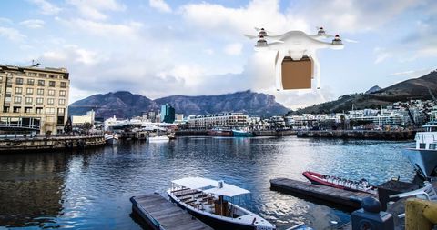 Drone Delivering Package Over Scenic Port City with Boats