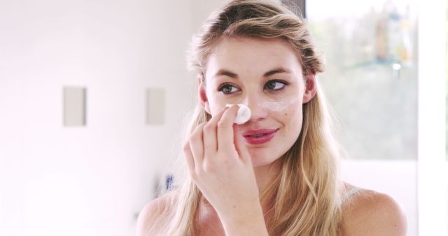 Young Woman Applying Face Cream in Bathroom - Download Free Stock Images Pikwizard.com