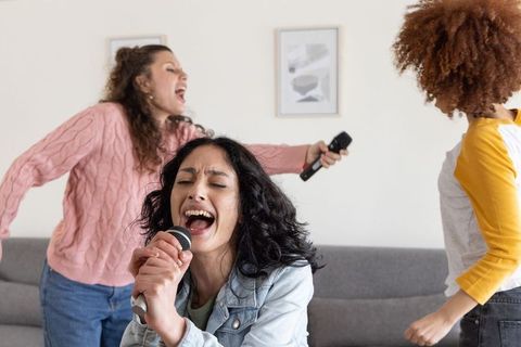 Friends singing karaoke at home celebrating with microphones and joyful energy