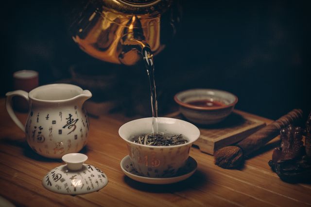 Authentic Chinese tea ceremony featuring brewing green tea using gold teapot and porcelain tea set. Ideal for promoting cultural heritage, tea brands, wellness blogs, tea events, Asian culture platforms, and traditional practices advertising.