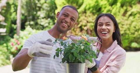 Joyful biracial couple enjoying gardening together outdoors