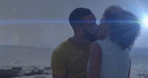Romantic couple sharing kiss on beach at sunset