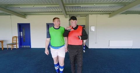 Soccer coach mentoring player in clubhouse corridor