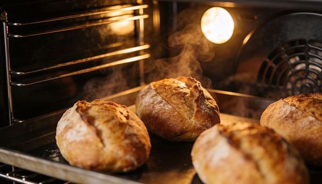 Baking artisan sourdough loaves steaming in hot oven with golden crusts