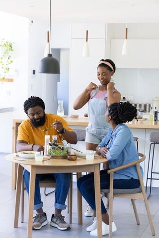 African american family sharing healthy breakfast and laughing in bright modern kitchen