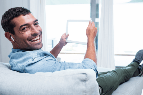 young man smiling on couch holding transparent tablet screen - Download Free Stock Videos Pikwizard.com