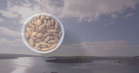 Almonds in Ceramic Bowl Over Tranquil Coastal Scenery