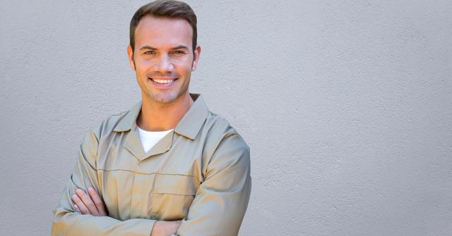 Portrait of serviceman standing with arms crossed against concrete background