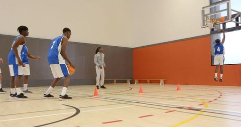 Basketball Players Practicing Layup Techniques in Gymnasium