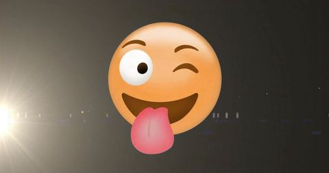 Playful winking tongue-out emoji floating on dark stage with spotlight flare emoticon