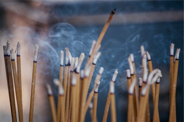 Burning incense sticks releasing wisps of smoke, often used in spiritual or meditative practices. Ideal for use in articles about spirituality, mindfulness, meditation, cultural rituals, relaxation, and holistic health improvements.