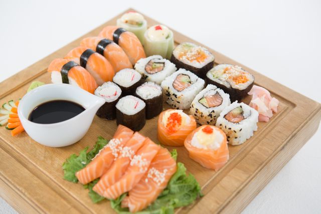Set of assorted sushi served on wooden tray against white background