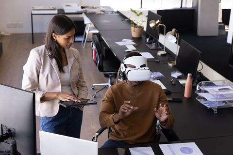 Coworkers Collaborating with VR Headset in Modern Office Environment