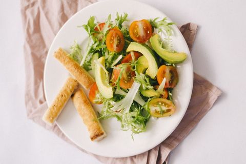 Fresh avocado and cherry tomato salad featuring frisée greens and toasted breadsticks
