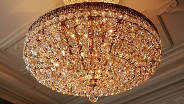 Glistening crystal chandelier illuminating grand ceiling with gold frame and ornate detail