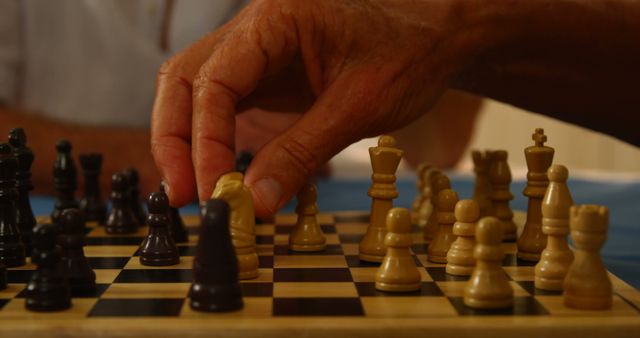 Elderly individual thoughtfully moving a chess piece on a wooden chessboard, signifying strategic thinking and mental exercise. Ideal for articles related to senior mental health, strategy games, or retirement activities. Could be used in promotions for board games or leisure activities.