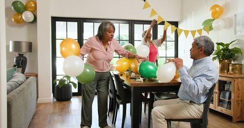 Senior Friends Preparing for Birthday Celebration with Balloons