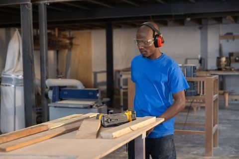 Carpenter measuring wood planks on workbench in industrial woodworking shop with tools