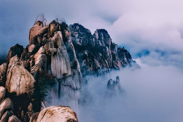 This scene's misty mountains and rocky cliffs create a dramatic and tranquil backdrop perfect for nature and travel blogs, wallpapers, or adventure tourism promotions. Ideal for depicting the beauty of the wilderness and promoting outdoor activities such as hiking and exploring remote areas.