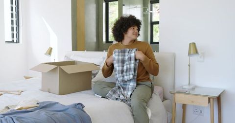 Person organizing clothes at home in bright bedroom