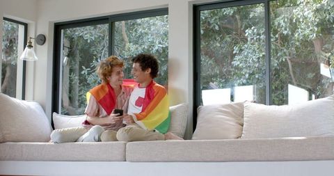 Gay Couple With Rainbow LGBT Flag Relaxing at Home
