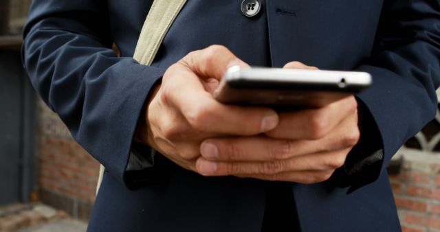 A middle-aged businessman in a suit is focused on his smartphone, with copy space. His engagement with the device suggests he might be checking important emails or scheduling meetings.