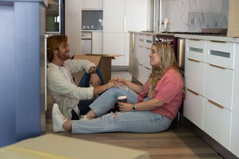 Couple enjoying coffee break amidst moving boxes
