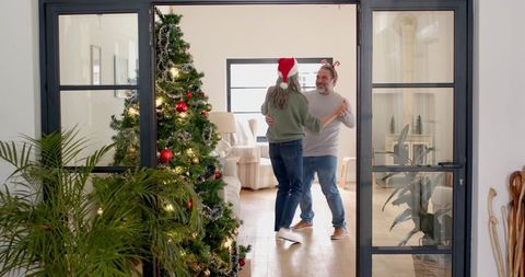 Festive couple dancing near christmas tree in cozy living room