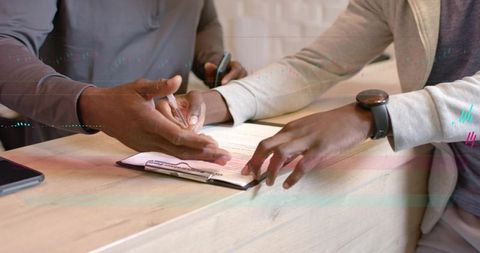 Staff guiding client signing registration form at reception counter, hands close-up