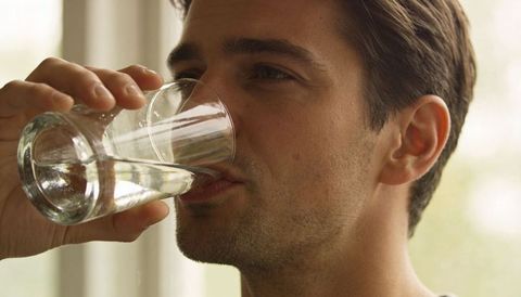 Man Drinking Water from Glass by Sunlit Window, Closeup Portrait for Hydration Lifestyle