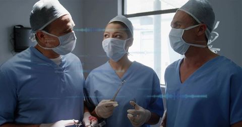 Surgical team preparing for operation holding forceps and retractors wearing blue scrubs