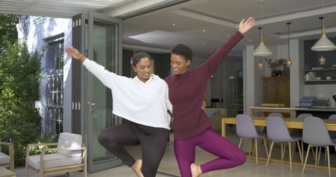 Diverse women practicing yoga at home terrace