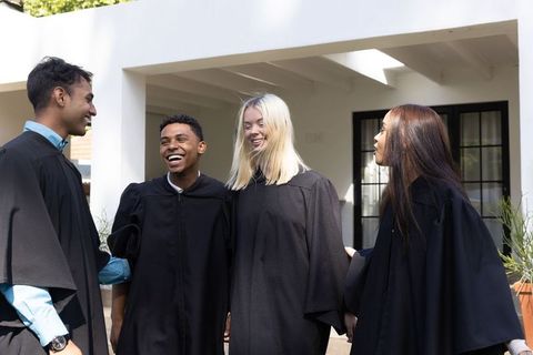 Diverse Graduates Laughing in Traditional Robes Outdoors