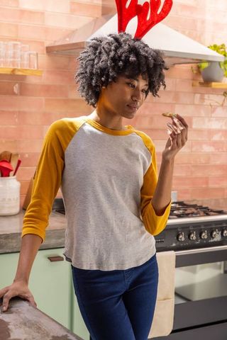 Festive African American Woman Enjoying a Cookie in Rustic Kitchen