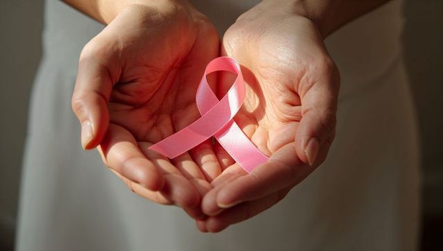 Hands Holding Pink Ribbon Representing Breast Cancer Awareness