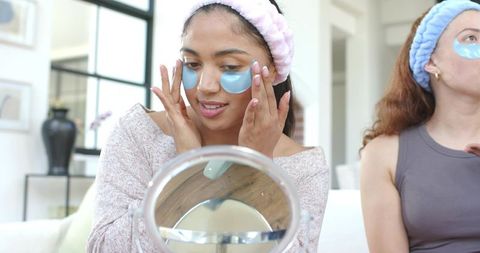 Women applying blue under-eye patches during at-home skincare session