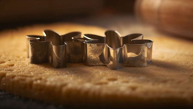 Metal flower-shaped cookie cutter on rolled dough in kitchen